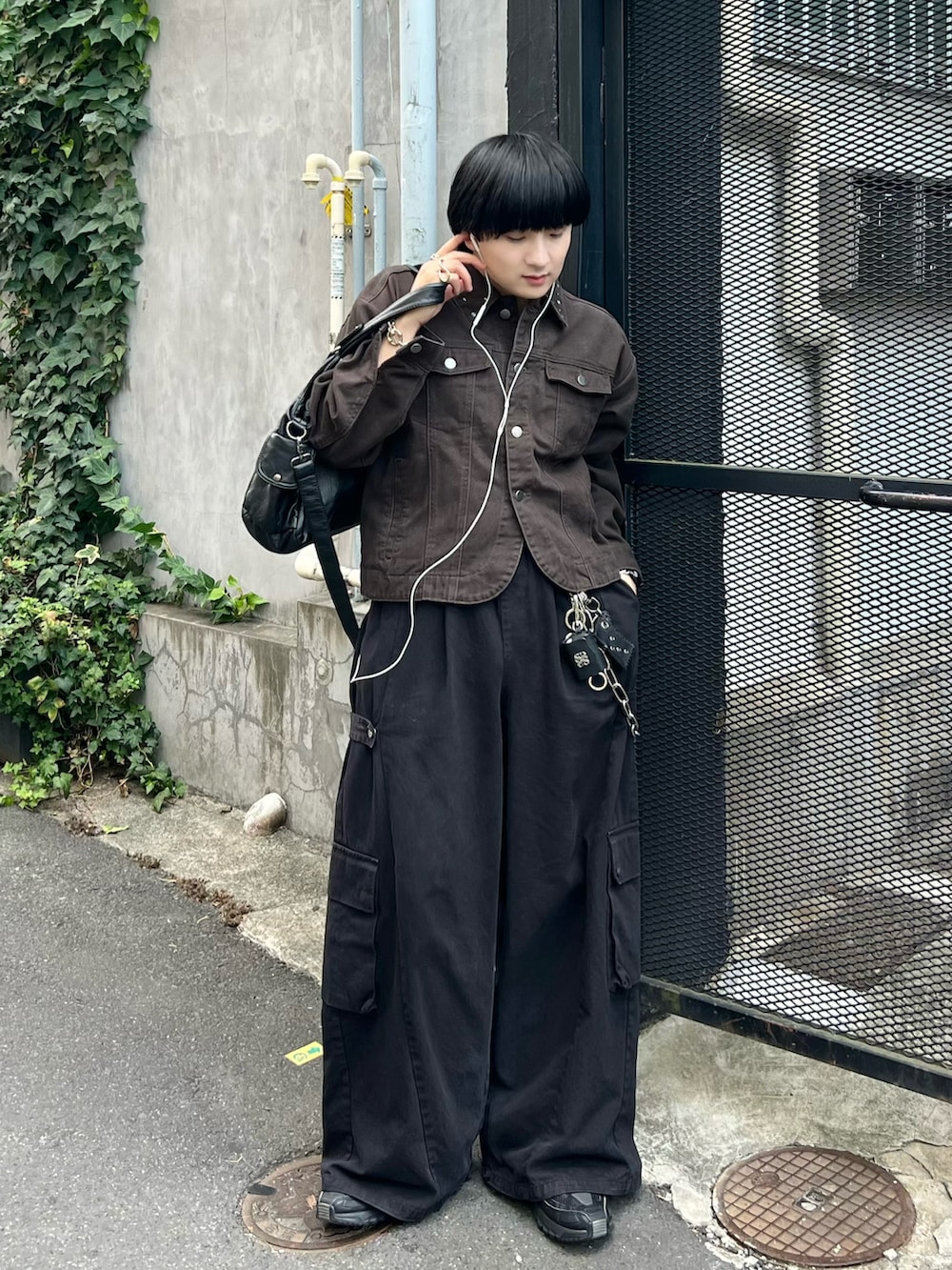 ブラック系のカーゴパンツ、ブラウン系のデニムジャケット、ブラック系のショルダーバッグを着用したメンズの秋コーディネートの3枚目の写真