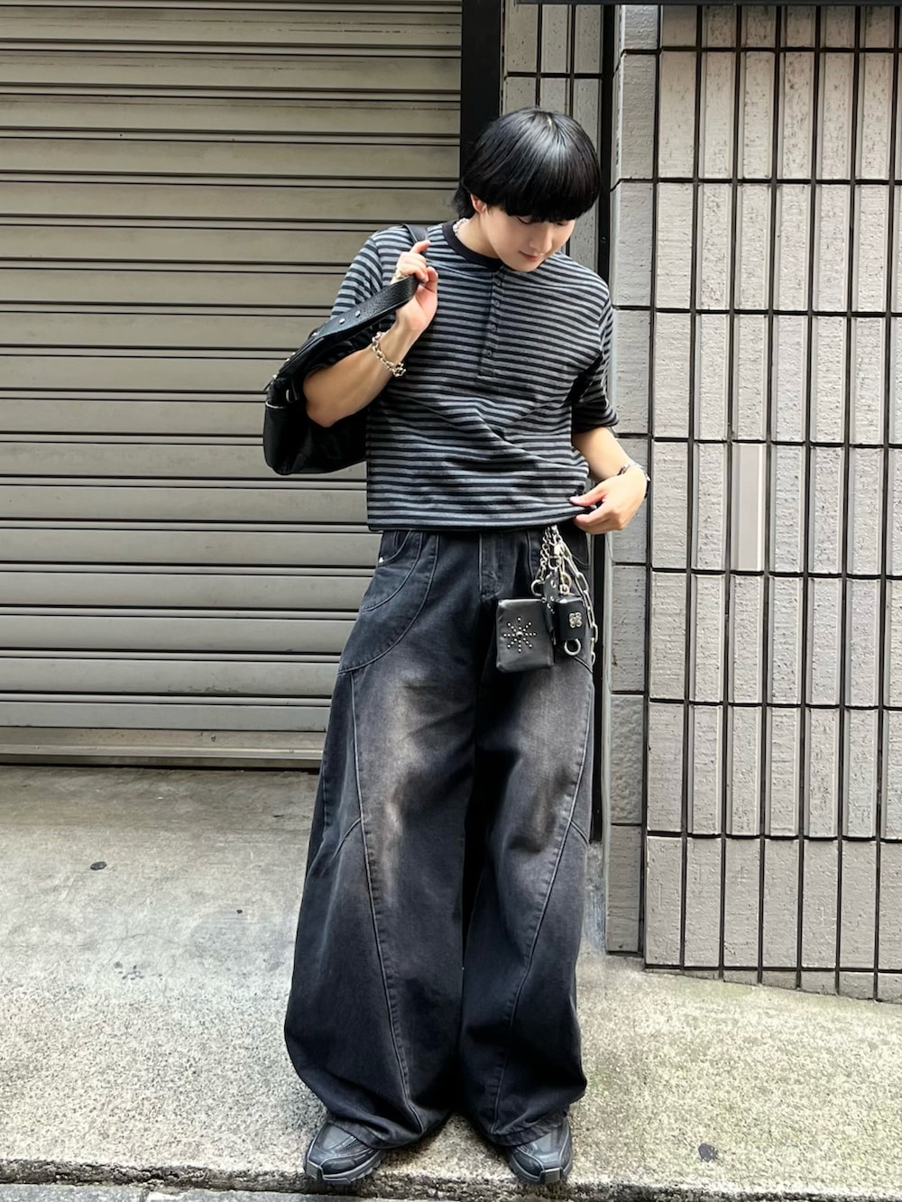 ブラック系のデニムパンツ、ブラック系のスニーカー、ブラック系のショルダーバッグを着用したメンズの秋コーディネートの3枚目の写真