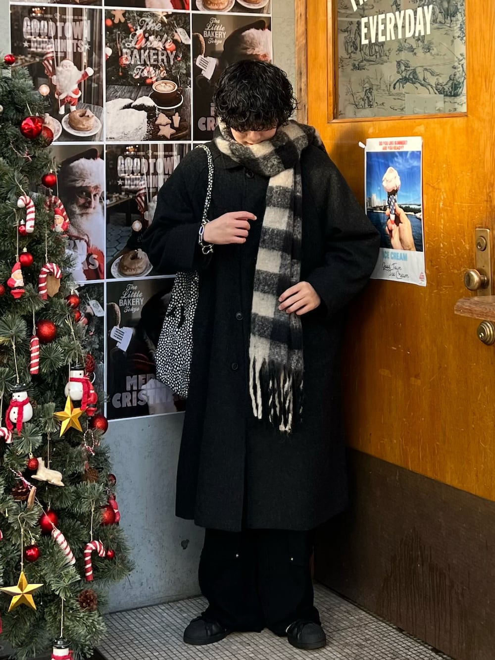 ブラック系のステンカラーコート、グレー系のトートバッグ、ブラック系のカーゴパンツを着用したメンズの冬コーディネートの2枚目の写真