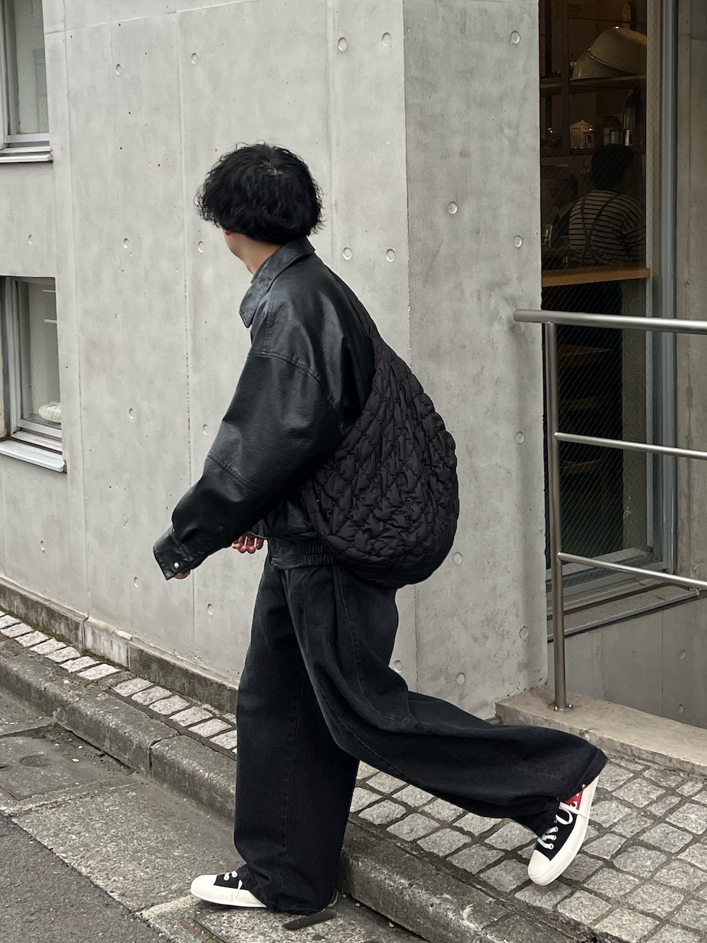 ブラック系のデニムパンツ、ブラック系のスニーカー、ホワイト系のショルダーバッグを着用したメンズの春コーディネートの3枚目の写真