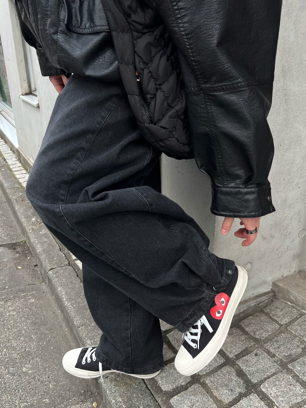 ブラック系のデニムパンツ、ブラック系のスニーカー、ホワイト系のショルダーバッグを着用したメンズの春コーディネートの4枚目の写真