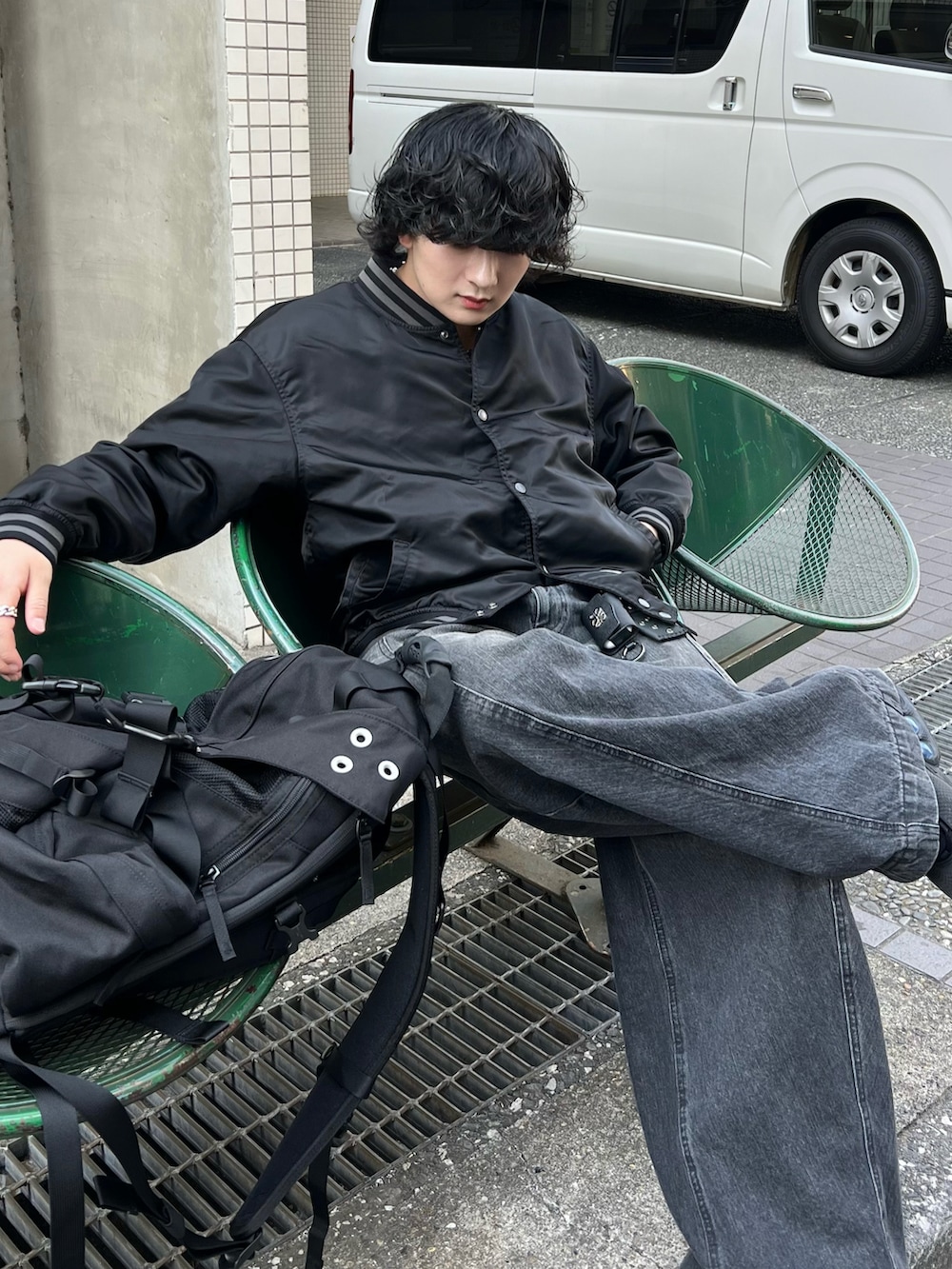 ブラック系のデニムパンツ、ブラック系のブルゾン、ブラック系のバックパック/リュックを着用したメンズの春コーディネートの2枚目の写真