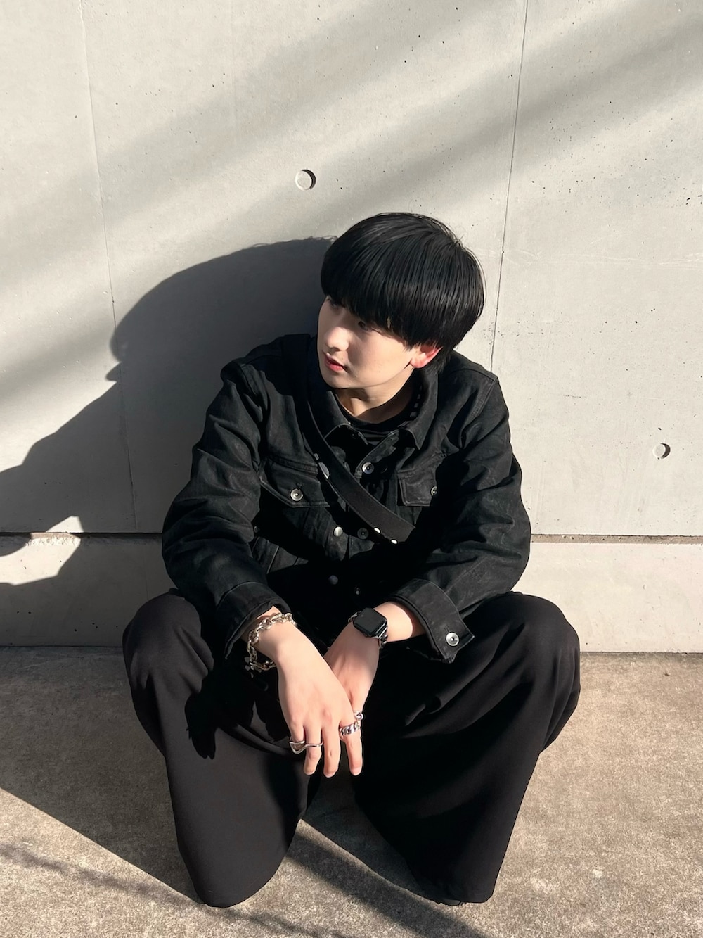 ブラック系のデニムジャケット、ブラック系のTシャツ/カットソー、ブラック系のスラックスを着用したメンズの春コーディネートの4枚目の写真