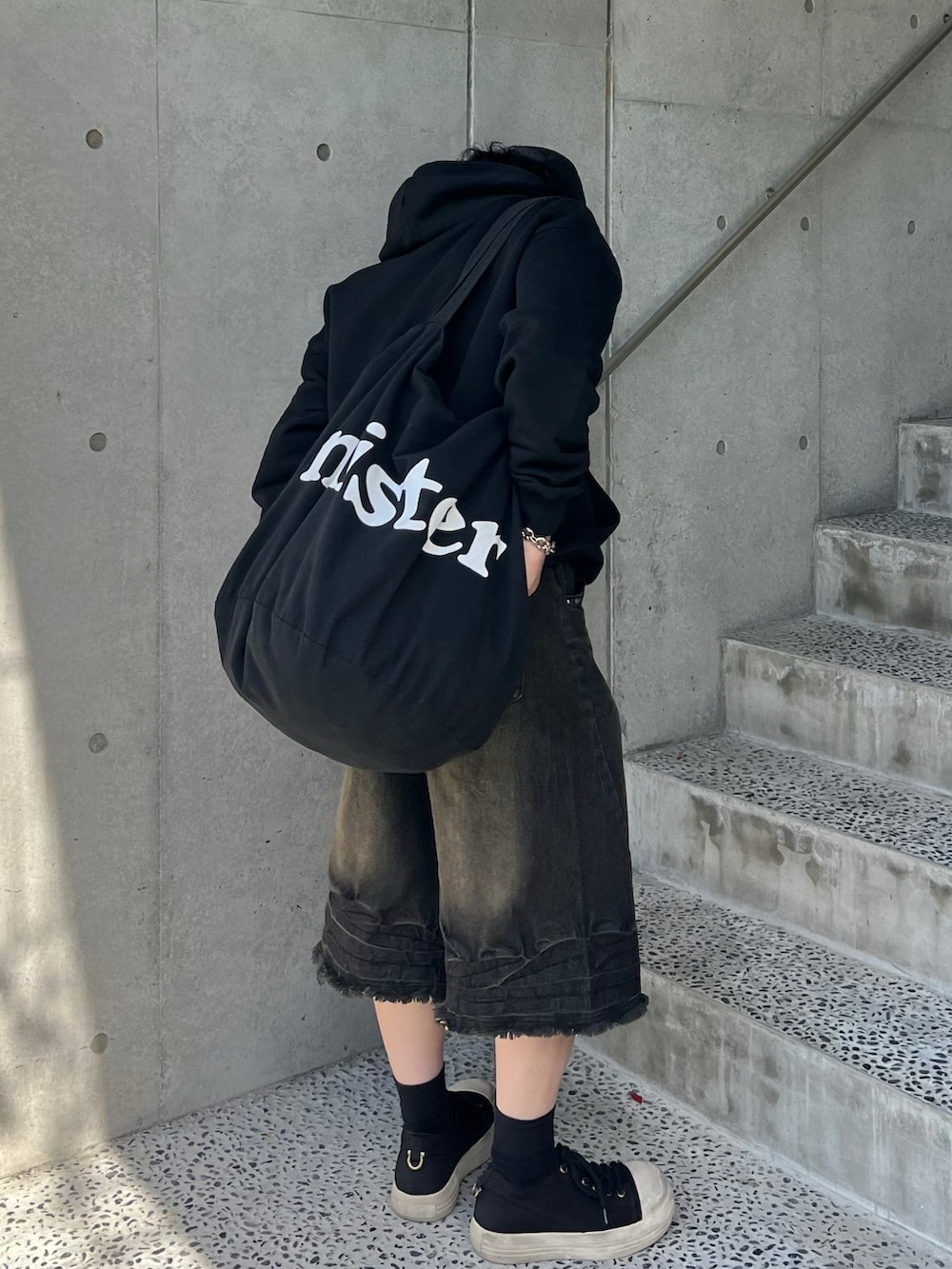 ブラック系のデニムパンツ、ブラック系のスニーカー、ブラック系のパーカーを着用したメンズの春コーディネートの3枚目の写真