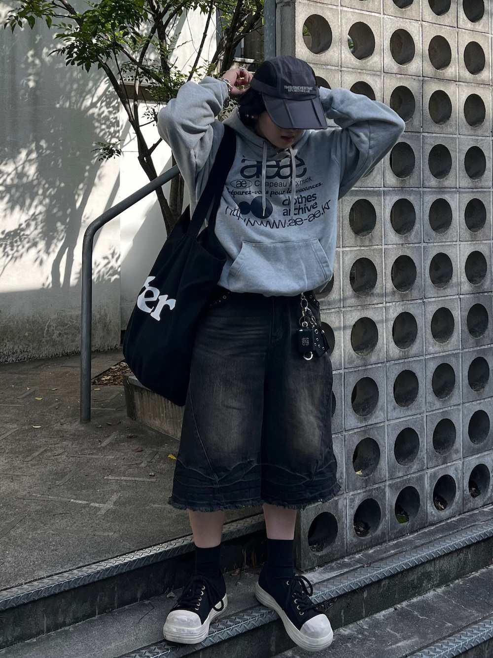 ブラック系のデニムパンツ、グレー系のパーカー、ブラック系のスニーカーを着用したメンズの春コーディネートの2枚目の写真