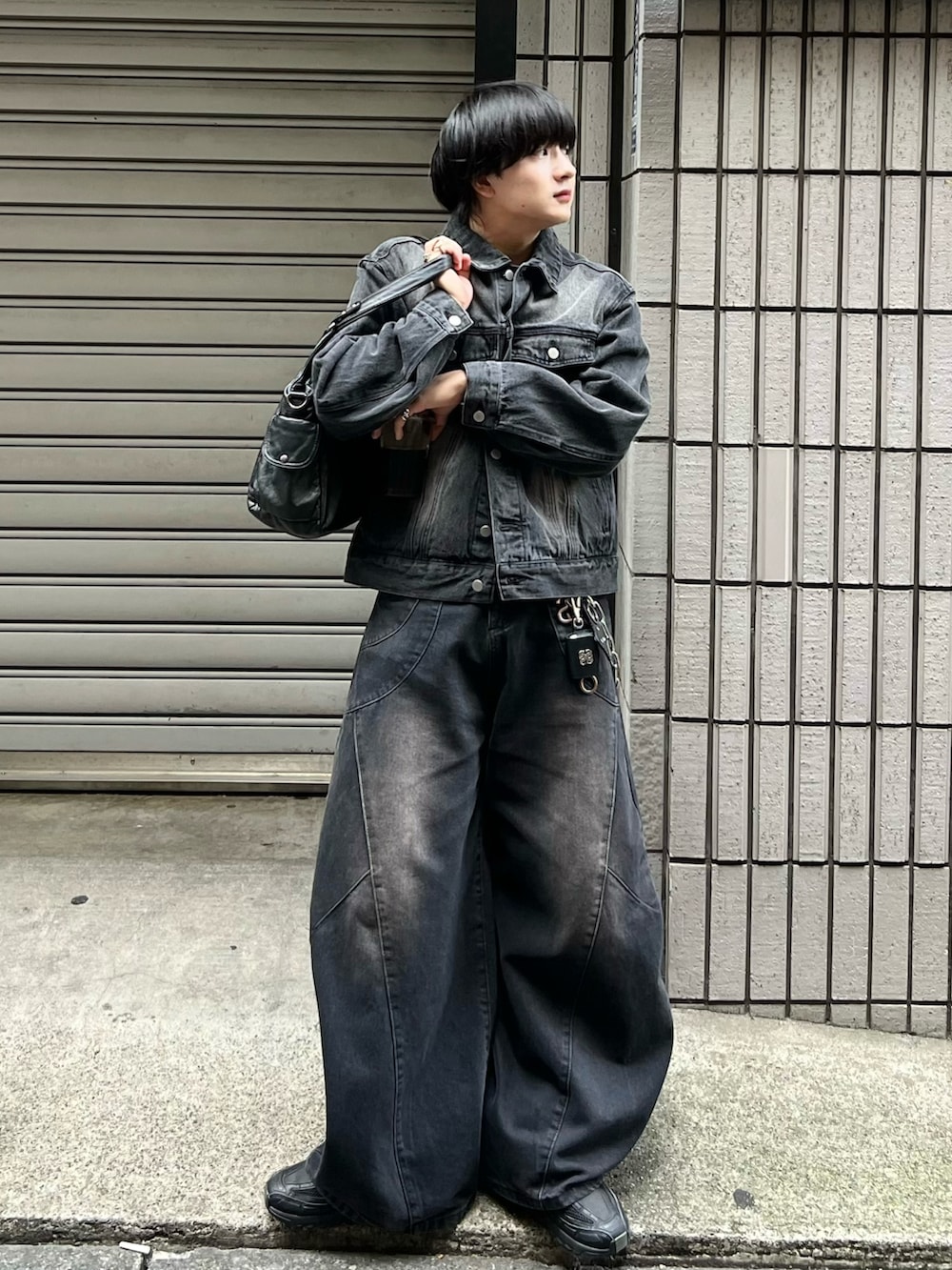 ブラック系のデニムジャケット、ブラック系のデニムパンツ、ブラック系のショルダーバッグを着用したメンズの秋コーディネートの3枚目の写真