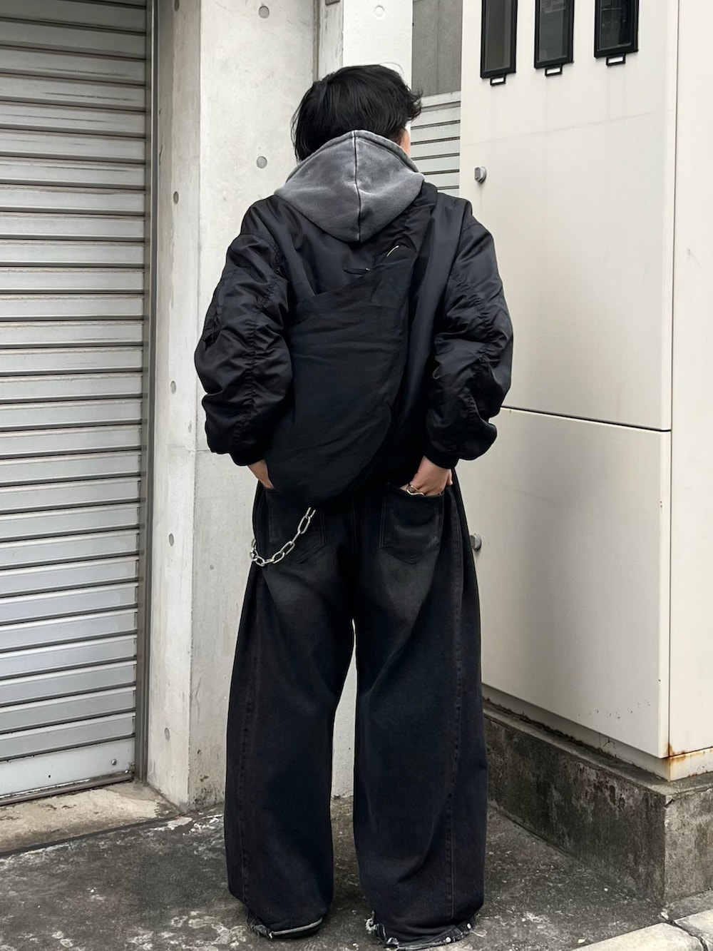 ブラック系のMA-1、グレー系のパーカー、ブラック系のショルダーバッグを着用したメンズの冬コーディネートの3枚目の写真