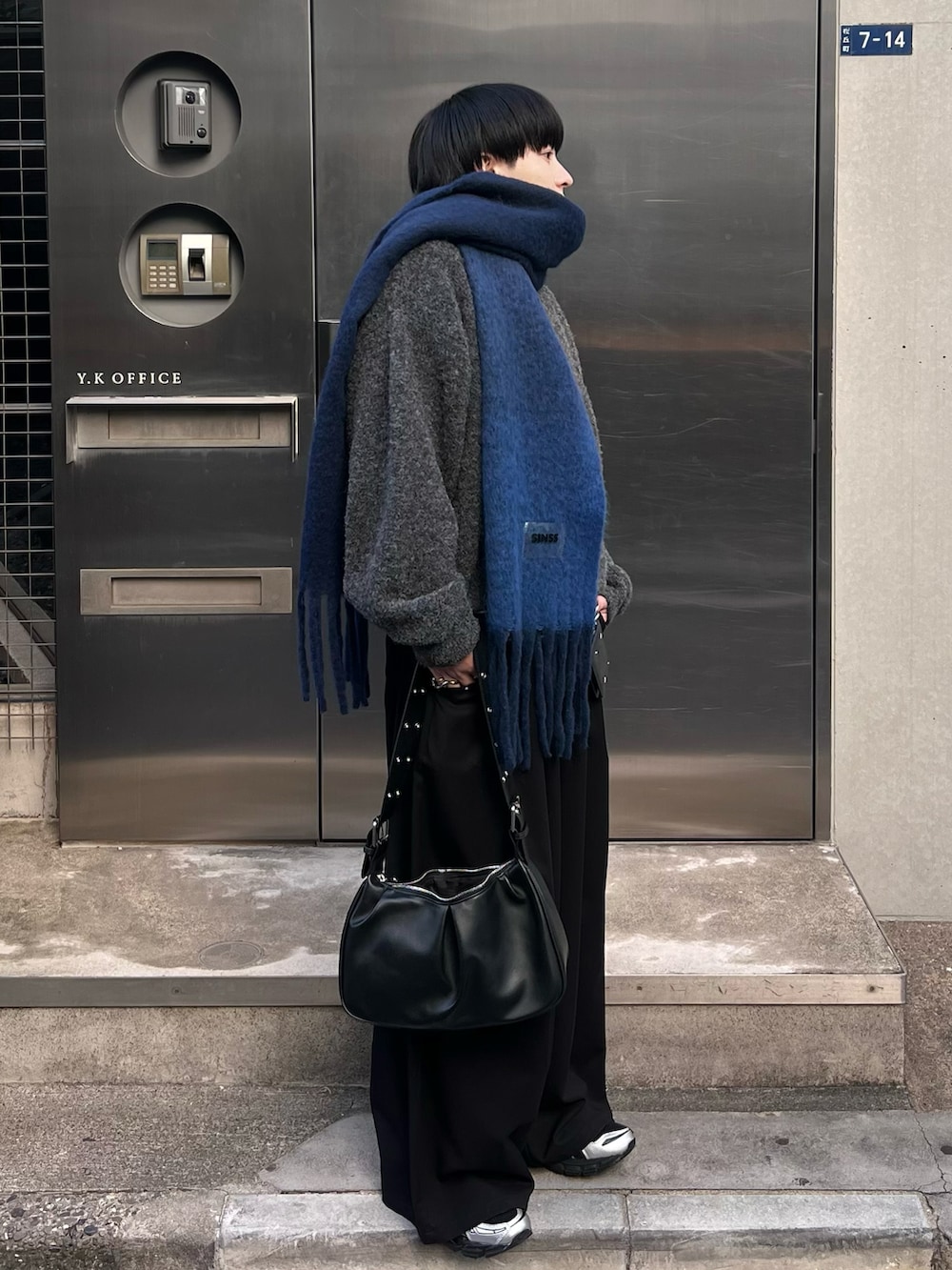 ブラック系のスラックス、グレー系のニット/セーター、ブラック系のTシャツ/カットソーを着用したメンズの冬コーディネートの2枚目の写真