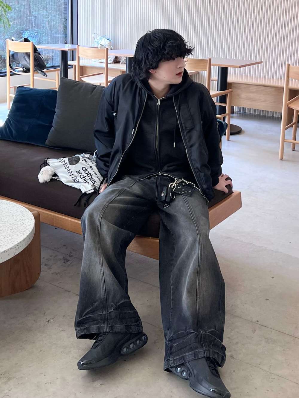 ブラック系のスニーカー、ブラック系のデニムパンツ、ブラック系のパーカーを着用したメンズの春コーディネートの2枚目の写真