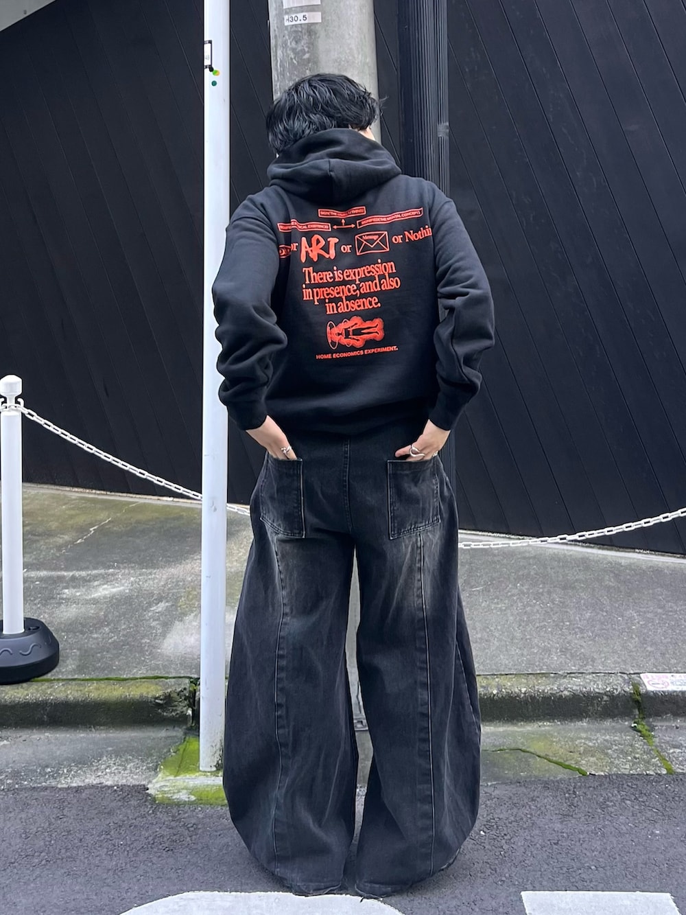 ブラック系のスウェット、ブラック系のデニムパンツ、ブラック系のスニーカーを着用したメンズの秋コーディネートの2枚目の写真