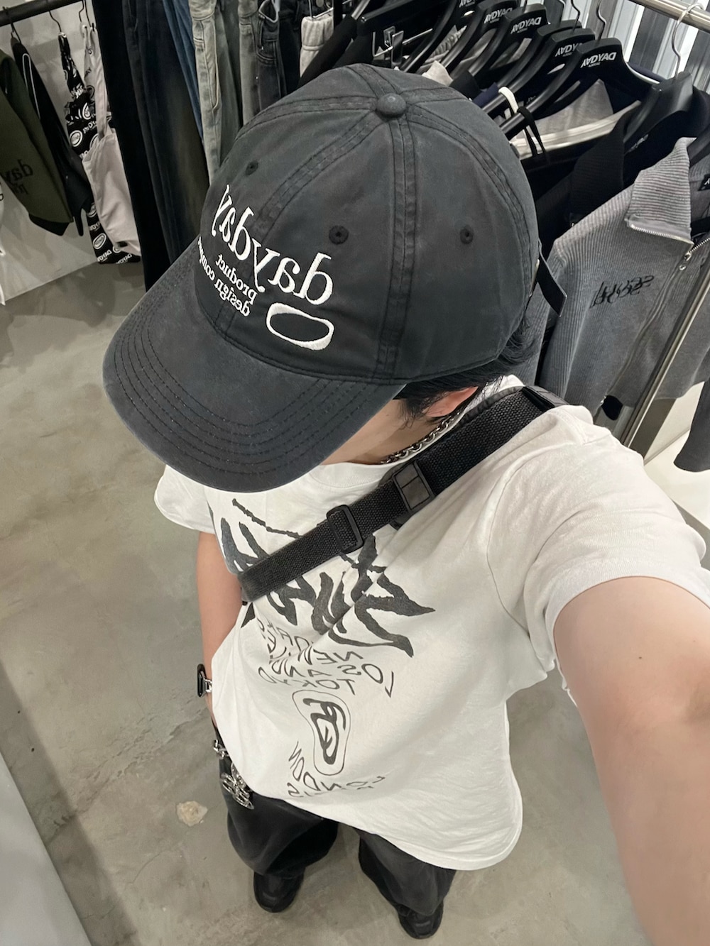 ホワイト系のTシャツ/カットソー、グレー系のショルダーバッグ、ブラック系のデニムパンツを着用したメンズの秋コーディネートの2枚目の写真