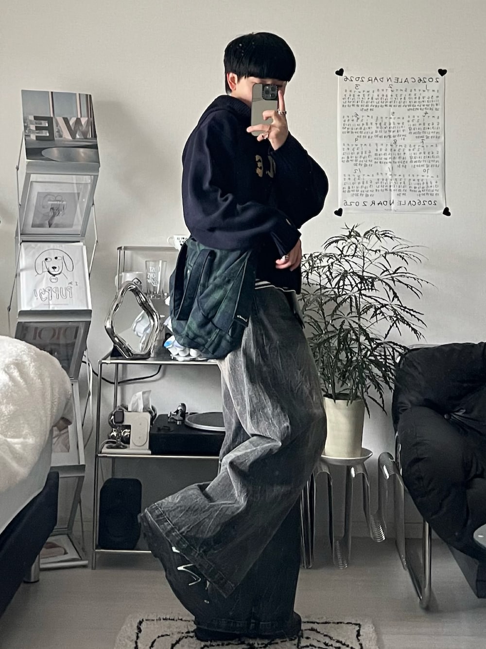 レッド系のパーカー、ブラック系のデニムパンツ、グリーン系のボストンバッグを着用したメンズの春コーディネートの2枚目の写真