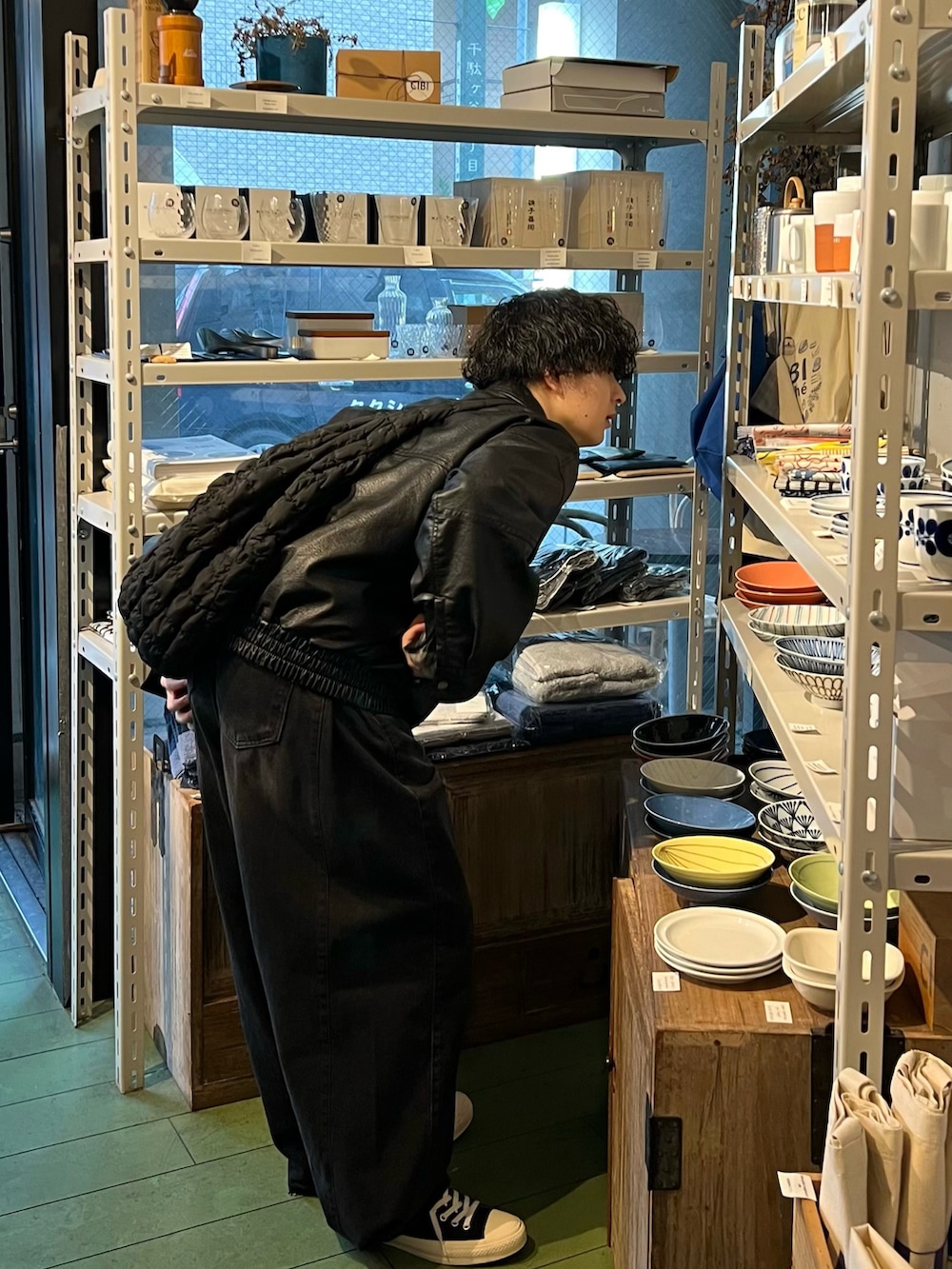 ブラック系のデニムパンツ、ブラック系のスニーカー、ホワイト系のショルダーバッグを着用したメンズの春コーディネートの2枚目の写真