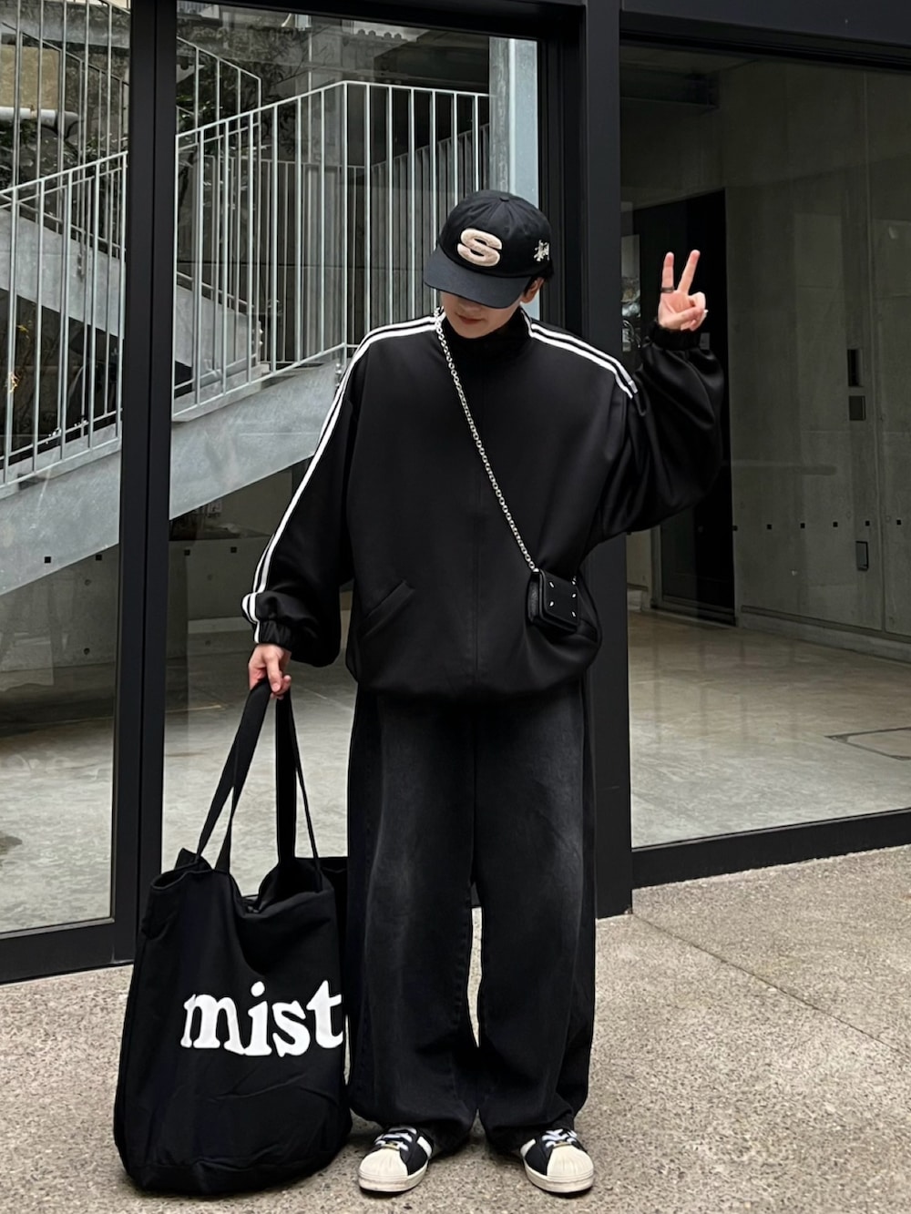 ブラック系のジャージ、ブラック系のトートバッグ、ブラック系のデニムパンツを着用したメンズの春コーディネートの2枚目の写真