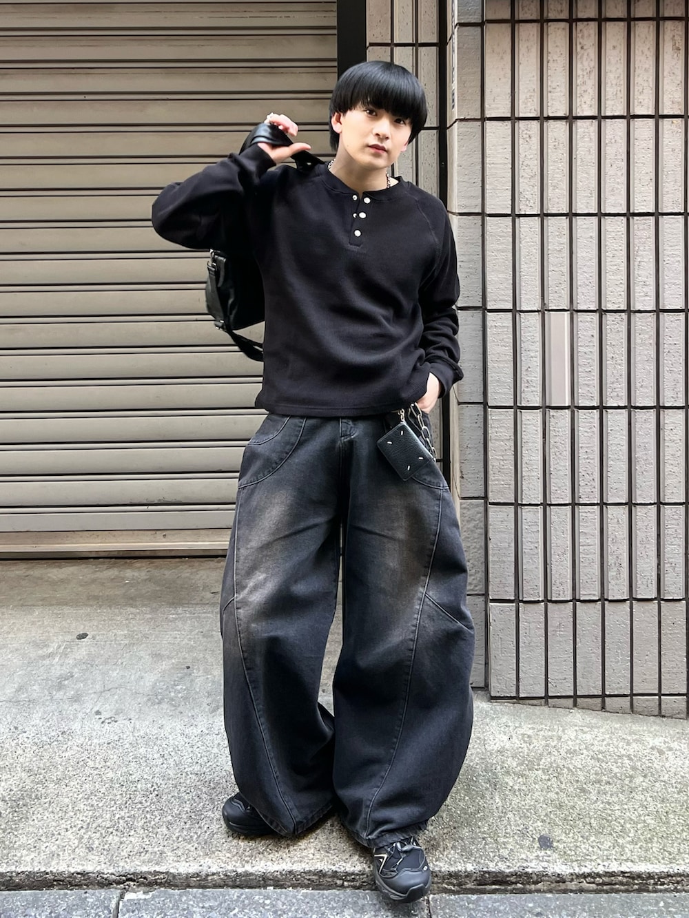 ブラック系のTシャツ/カットソー、ブラック系のデニムパンツ、ブラック系のショルダーバッグを着用したメンズの春コーディネートの2枚目の写真