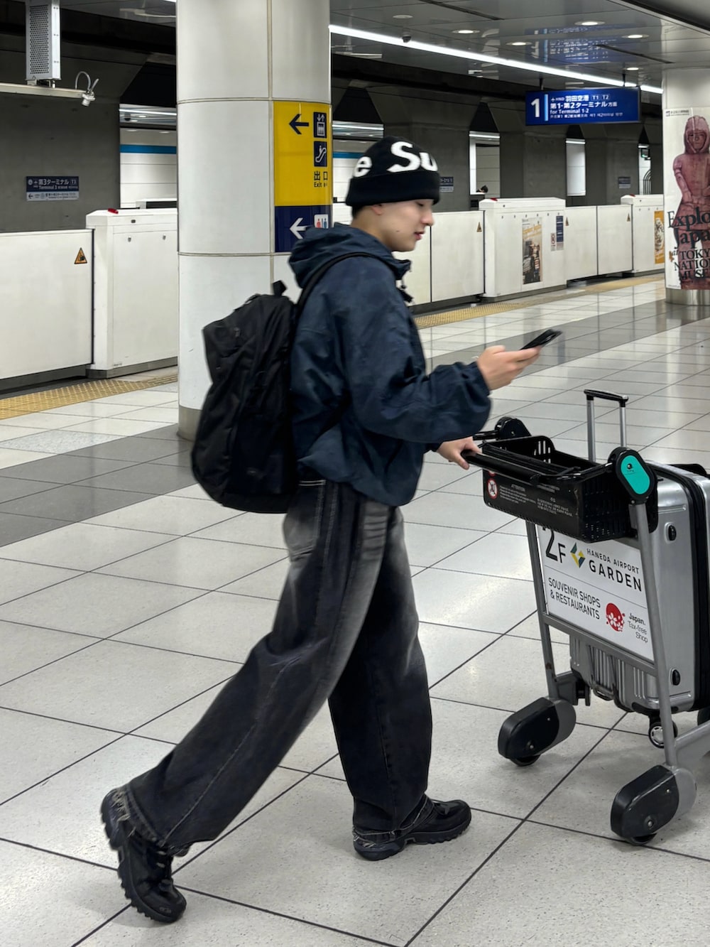 ブラック系のデニムパンツ、ブラック系のスニーカー、ブルー系のマウンテンパーカーを着用したメンズの夏コーディネートの2枚目の写真