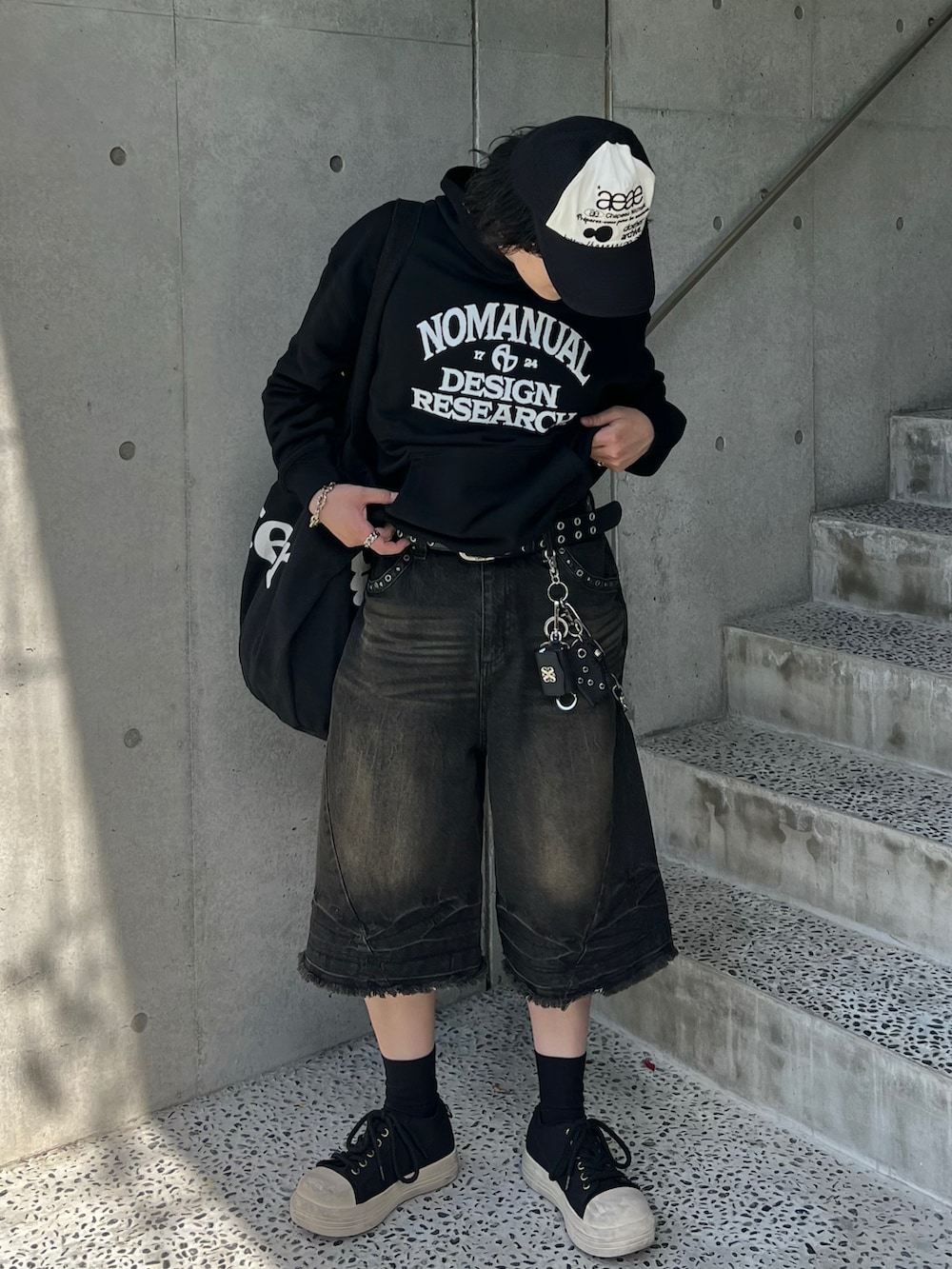 ブラック系のデニムパンツ、ブラック系のスニーカー、ブラック系のパーカーを着用したメンズの春コーディネートの2枚目の写真