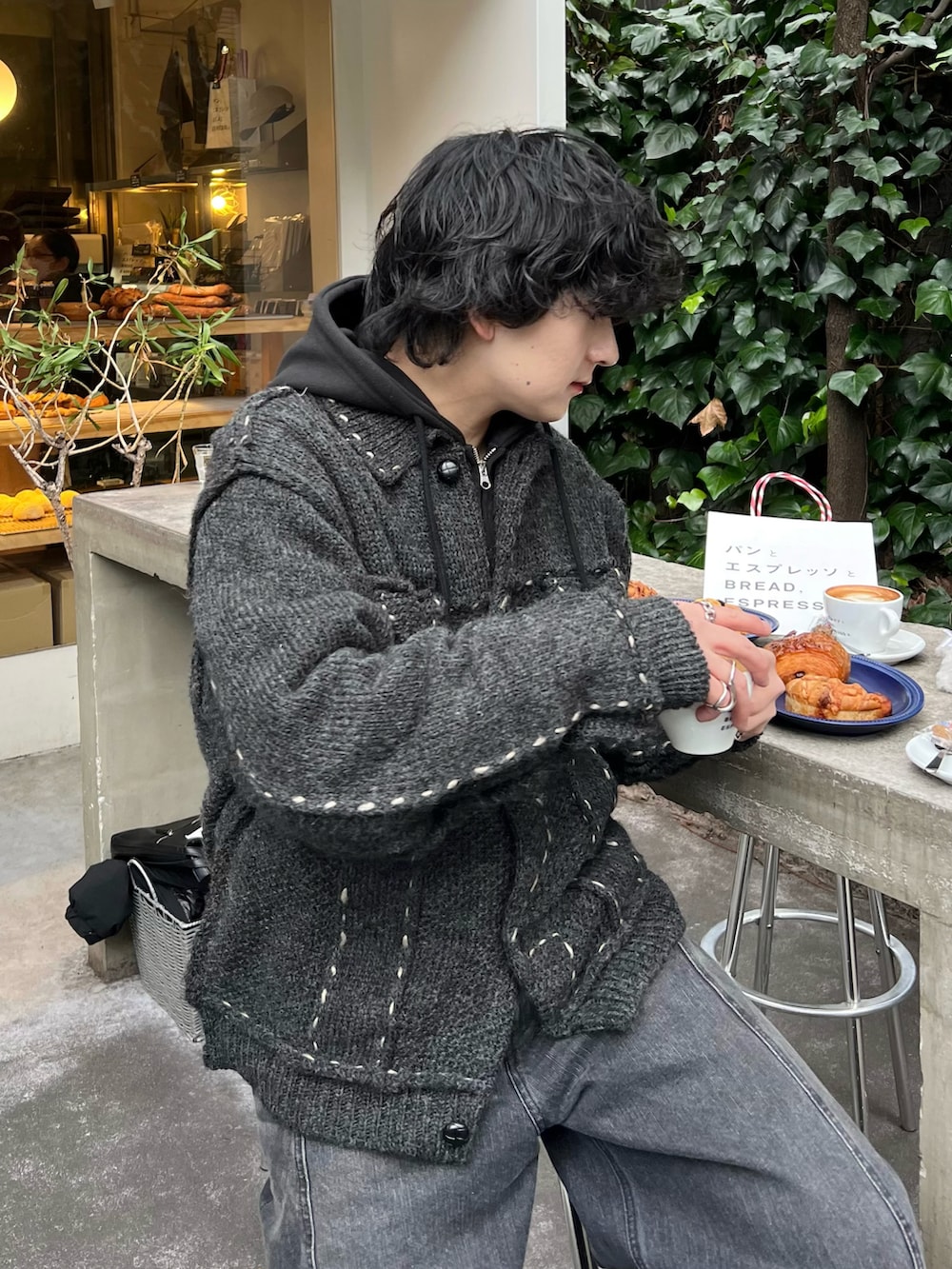 グレー系のカーディガン/ボレロ、ブラック系のパーカー、ブラック系のデニムパンツを着用したメンズの冬コーディネートの2枚目の写真