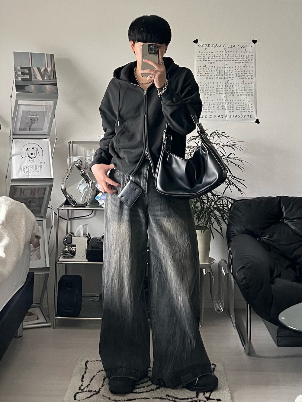 ブラック系のパーカー、ブラック系のデニムパンツ、ブラック系のハンドバッグを着用したメンズの春コーディネートの2枚目の写真