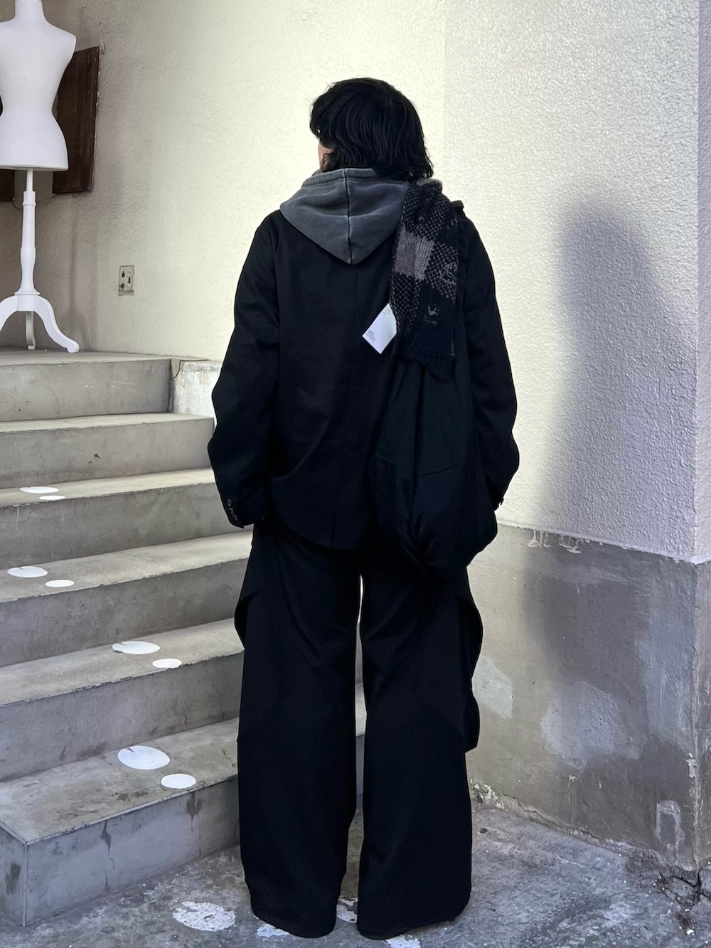 グレー系のパーカー、ブラック系のショルダーバッグ、ブラック系のスラックスを着用したメンズの冬コーディネートの3枚目の写真