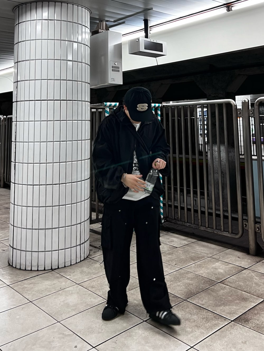 ホワイト系のTシャツ/カットソー、ブラック系のナイロンジャケット、ブラック系のカーゴパンツを着用したメンズの春コーディネートの3枚目の写真