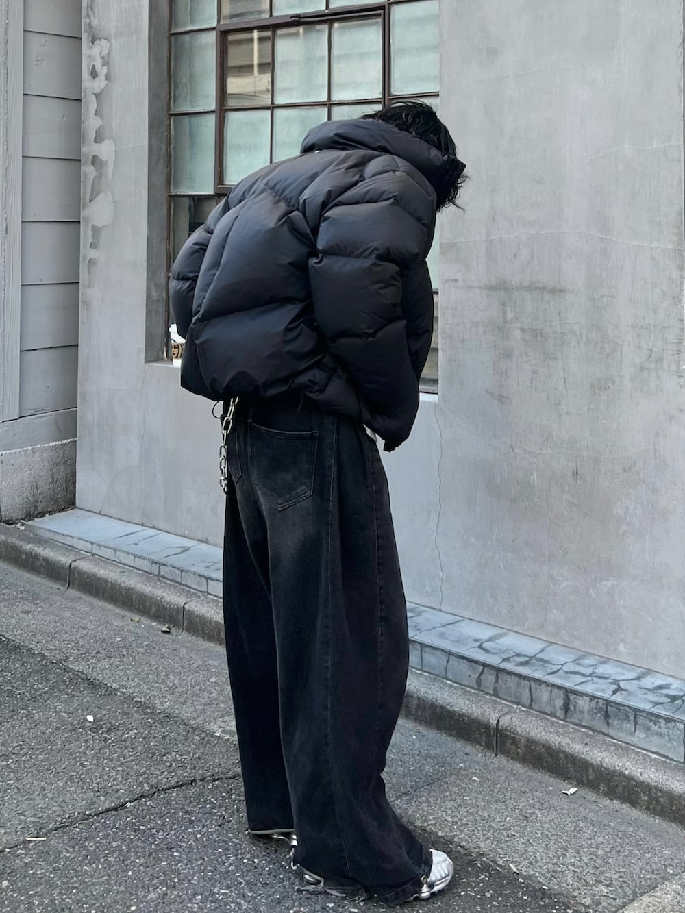 ブラック系のダウンジャケット/コート、グレー系のデニムパンツ、ホワイト系のTシャツ/カットソーを着用したメンズの冬コーディネートの2枚目の写真