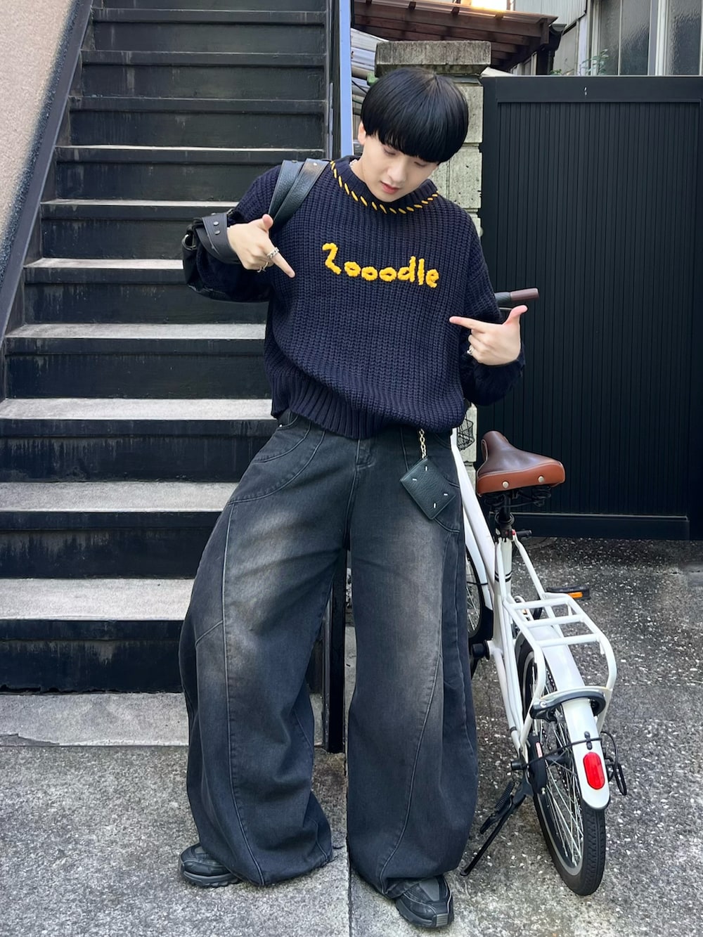 ブラック系のデニムパンツ、ブルー系のニット/セーター、ブラック系のショルダーバッグを着用したメンズの秋コーディネートの2枚目の写真