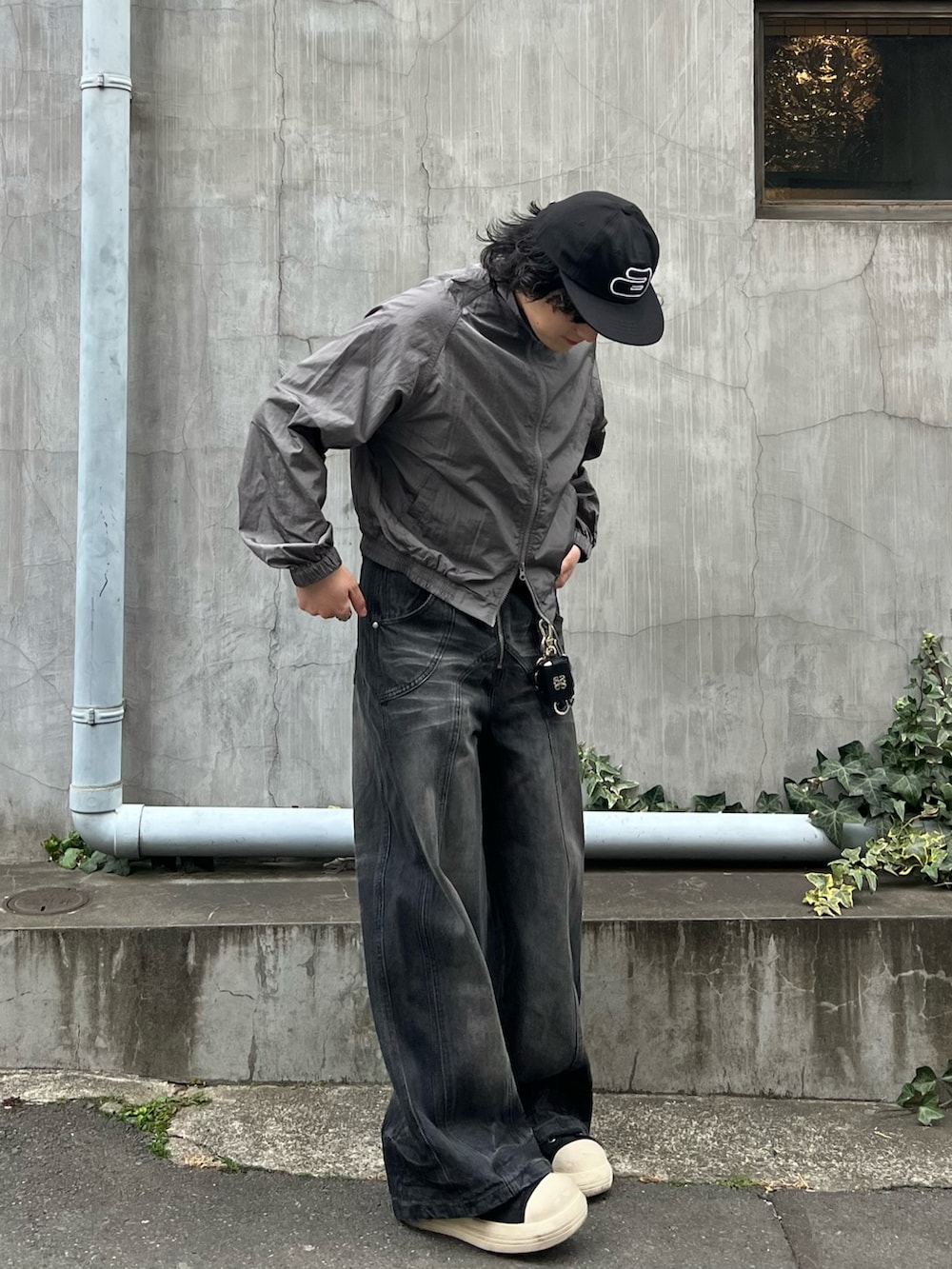 ブラック系のスニーカー、グレー系のナイロンジャケット、ブラック系のデニムパンツを着用したメンズの春コーディネートの3枚目の写真