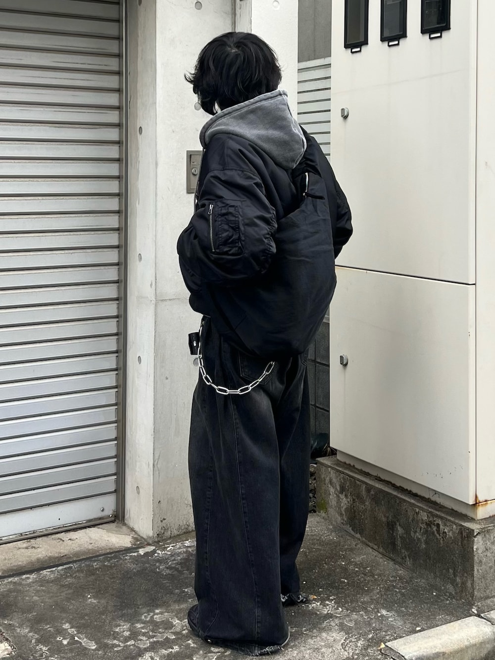 ブラック系のMA-1、グレー系のパーカー、ブラック系のショルダーバッグを着用したメンズの冬コーディネートの2枚目の写真