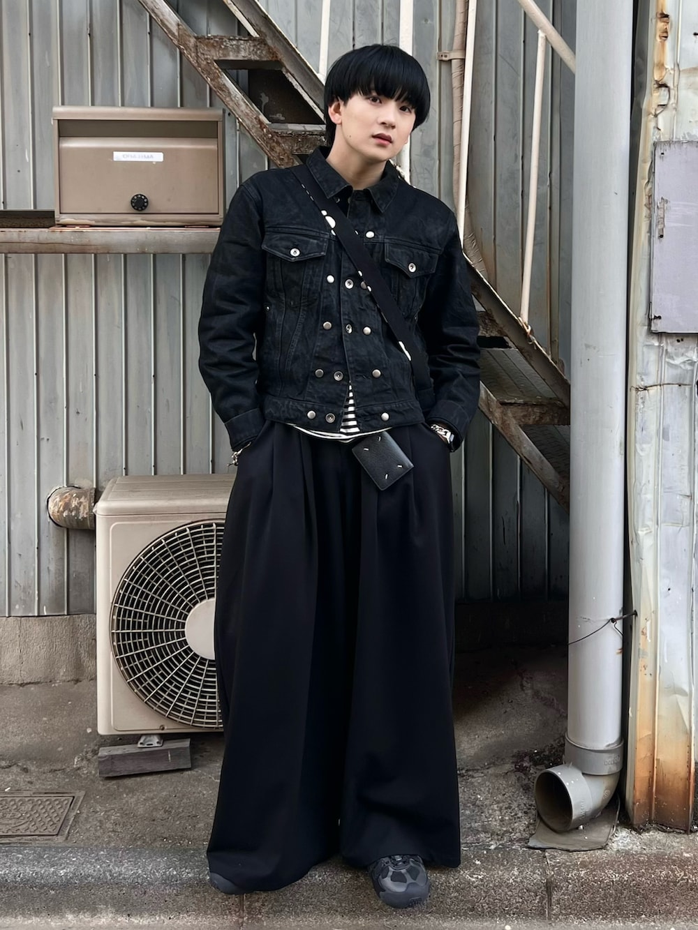 ブラック系のデニムジャケット、ブラック系のTシャツ/カットソー、ブラック系のスラックスを着用したメンズの春コーディネートの3枚目の写真