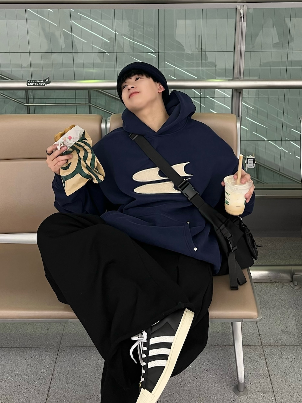 ブルー系のパーカー、グレー系のショルダーバッグ、ブラック系のスニーカーを着用したメンズの春コーディネートの2枚目の写真