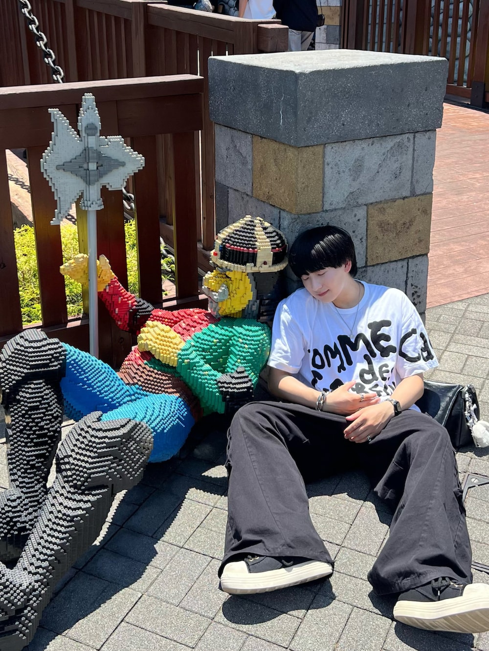 ブラック系のカーゴパンツ、ブラック系のスニーカー、ホワイト系のTシャツ/カットソーを着用したメンズの夏コーディネートの2枚目の写真