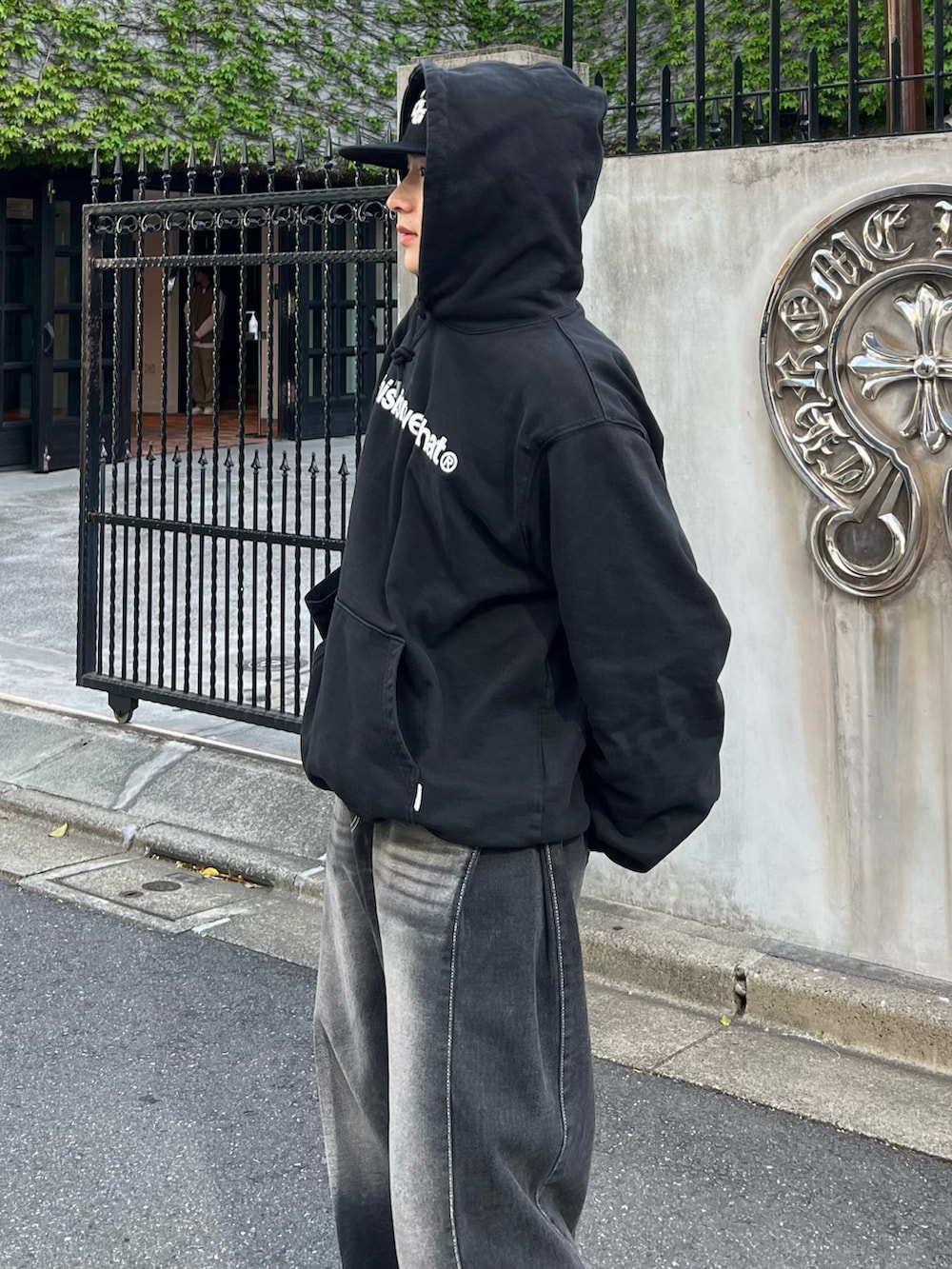 ブラック系のパーカー、ブラック系のデニムパンツ、ブラック系のトートバッグを着用したメンズの春コーディネートの3枚目の写真