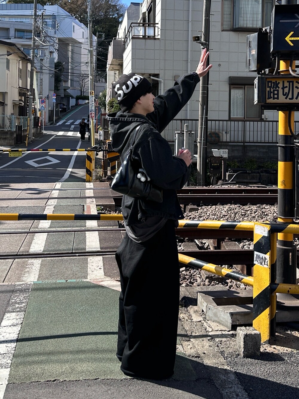 ブラック系のデニムジャケット、ブラック系のスウェットパンツ、ブラック系のスニーカーを着用したメンズの春コーディネートの3枚目の写真