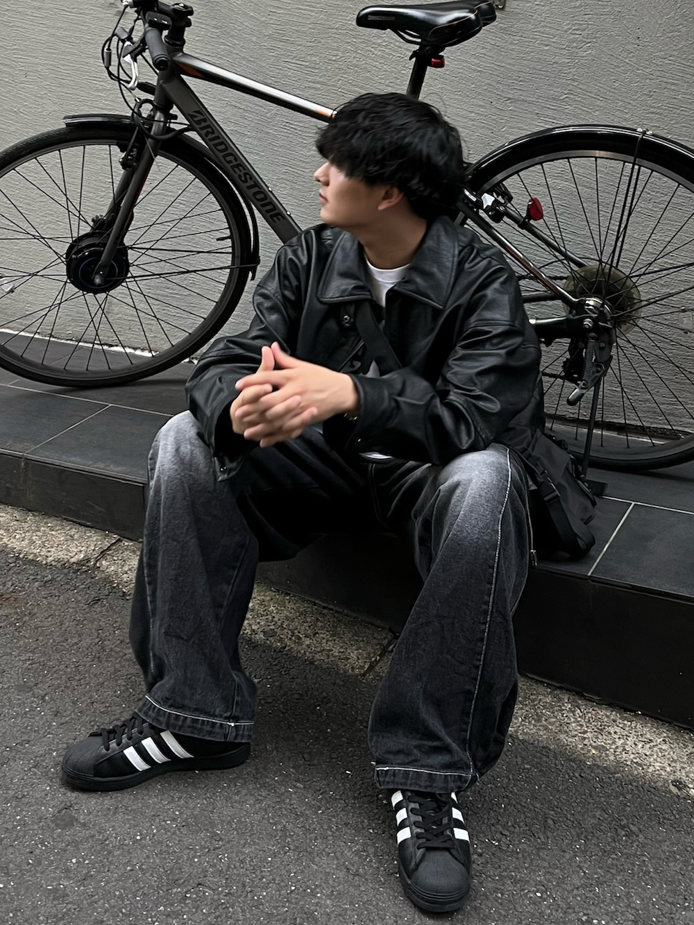 ブラック系のブルゾン、ホワイト系のTシャツ/カットソー、ブラック系のデニムパンツを着用したメンズの冬コーディネートの2枚目の写真