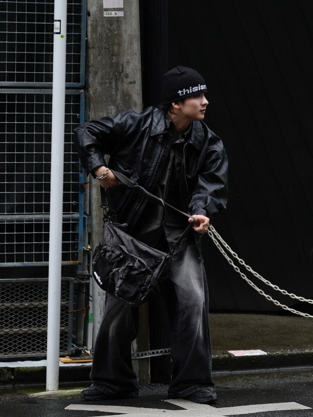 ブラック系のブルゾン、グレー系のショルダーバッグ、ブラック系のデニムパンツを着用したメンズの秋コーディネートの3枚目の写真