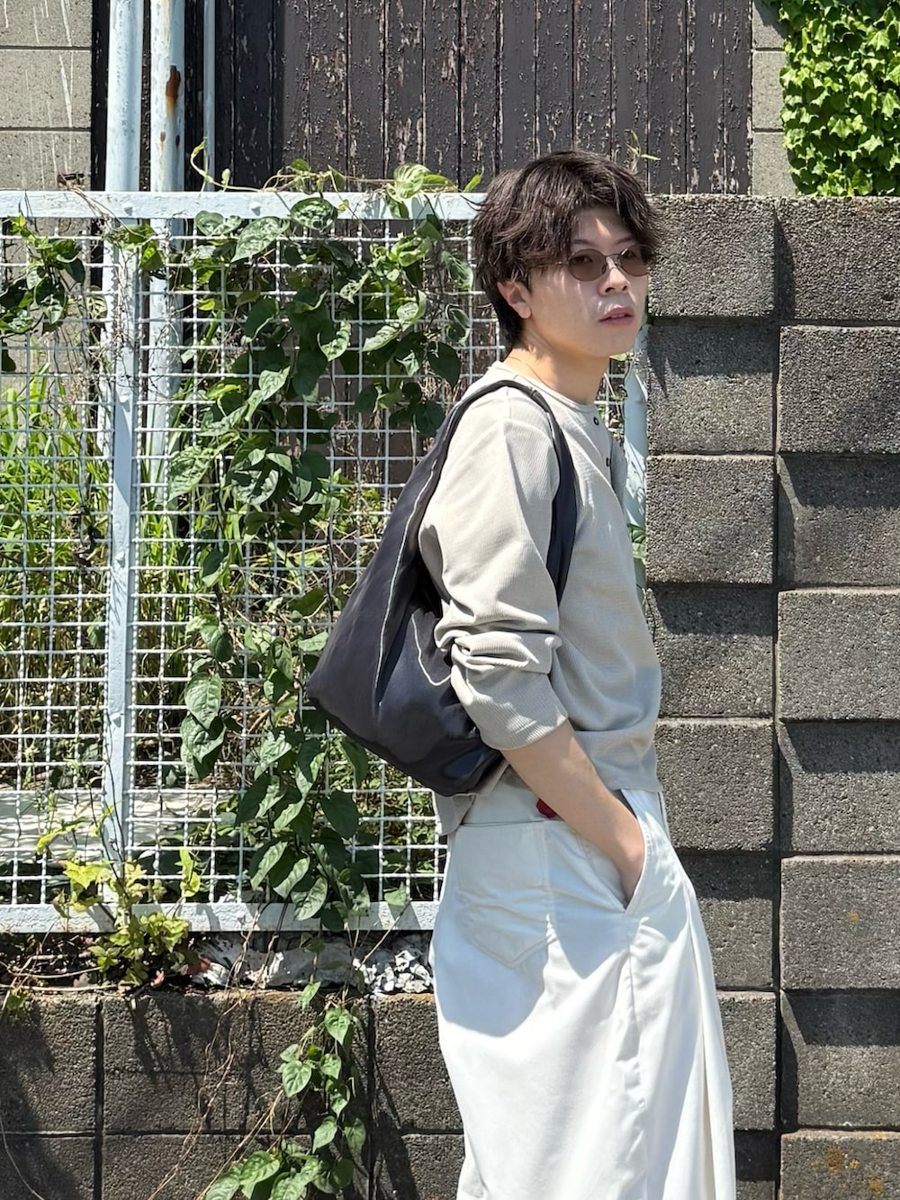 ベージュ系のTシャツ/カットソー、ホワイト系のその他パンツ、グレー系のハンドバッグを着用したメンズの春コーディネートの3枚目の写真