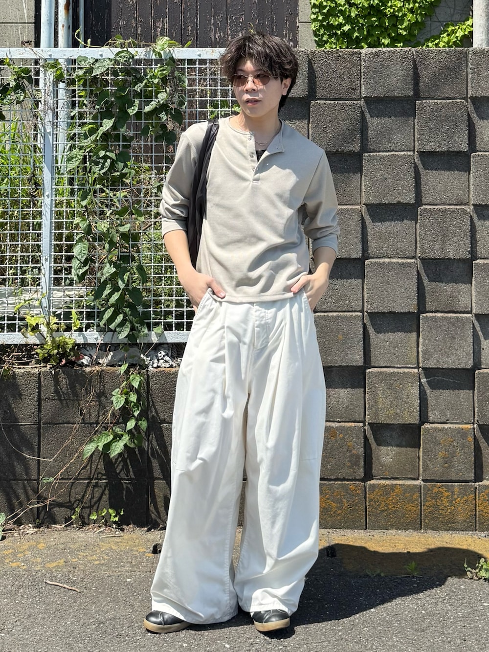 ベージュ系のTシャツ/カットソー、ホワイト系のその他パンツ、グレー系のハンドバッグを着用したメンズの春コーディネートの2枚目の写真