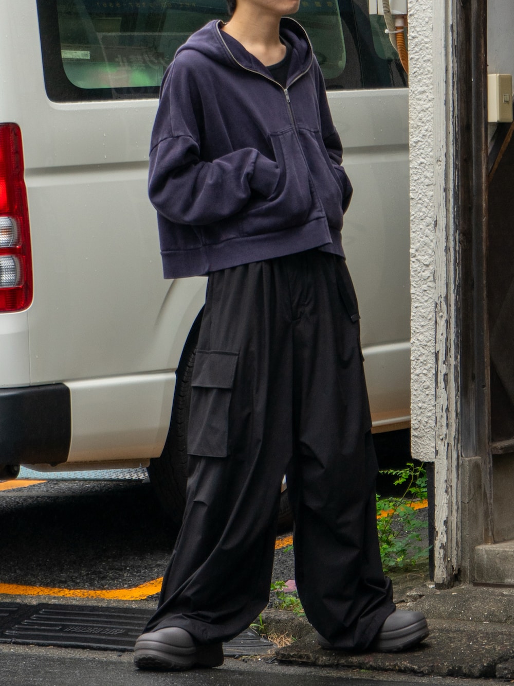 ブラック系のパーカー、ブラック系のカーゴパンツ、ブラウン系のサンダルを着用したメンズの秋コーディネートの4枚目の写真