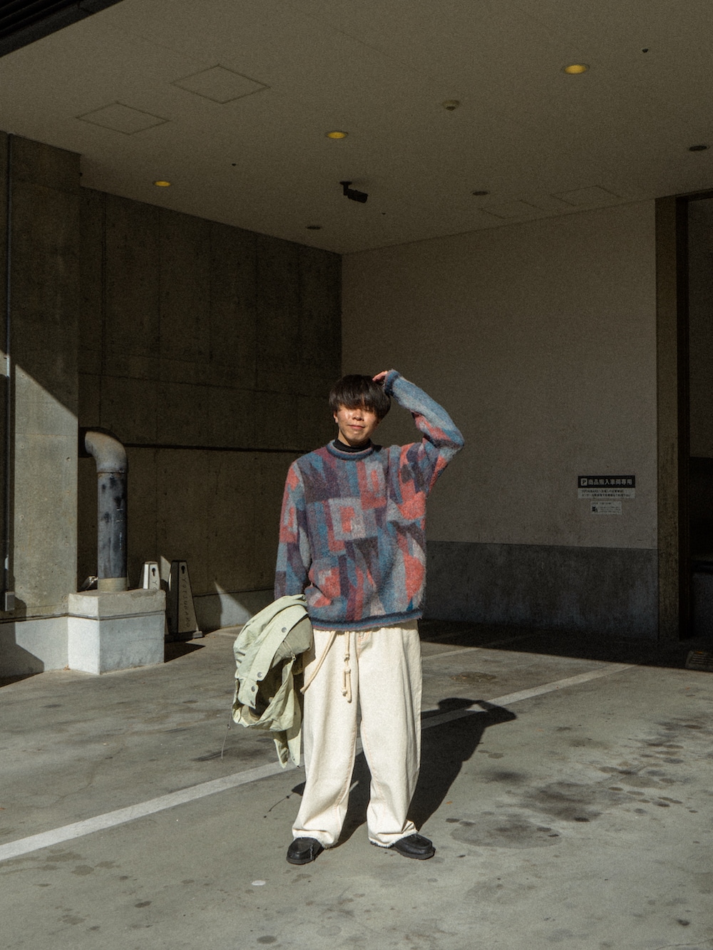 ブルー系のニット/セーター、ベージュ系のマウンテンパーカー、ブラック系のデニムパンツを着用したメンズの冬コーディネートの4枚目の写真