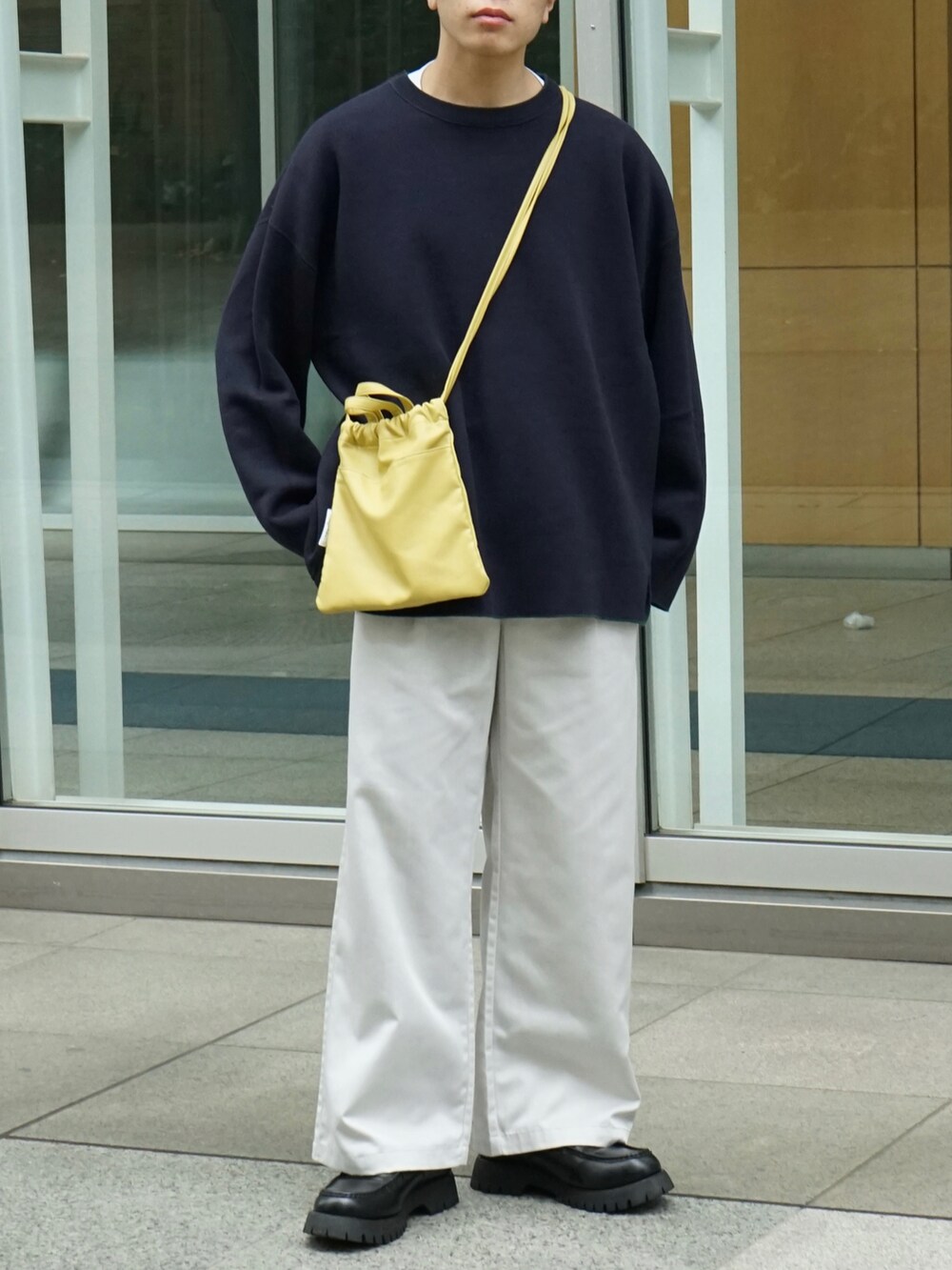 グリーン系のニット/セーター、ホワイト系のチノパンツ、イエロー系のショルダーバッグを着用したメンズの秋コーディネートの5枚目の写真