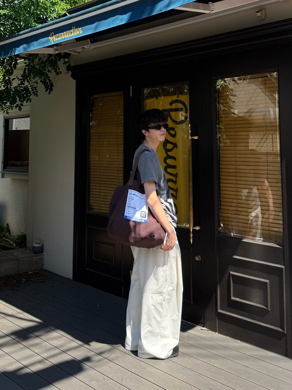 ホワイト系のその他パンツ、ブラウン系のトートバッグ、ブラック系のモカシン/デッキシューズを着用したメンズの夏コーディネートの3枚目の写真