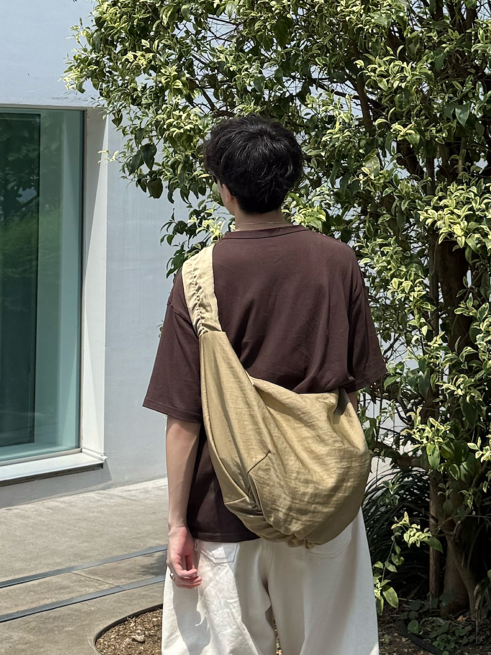 ブラウン系のTシャツ/カットソー、ベージュ系のショルダーバッグ、ホワイト系のデニムパンツを着用したメンズの秋コーディネートの3枚目の写真