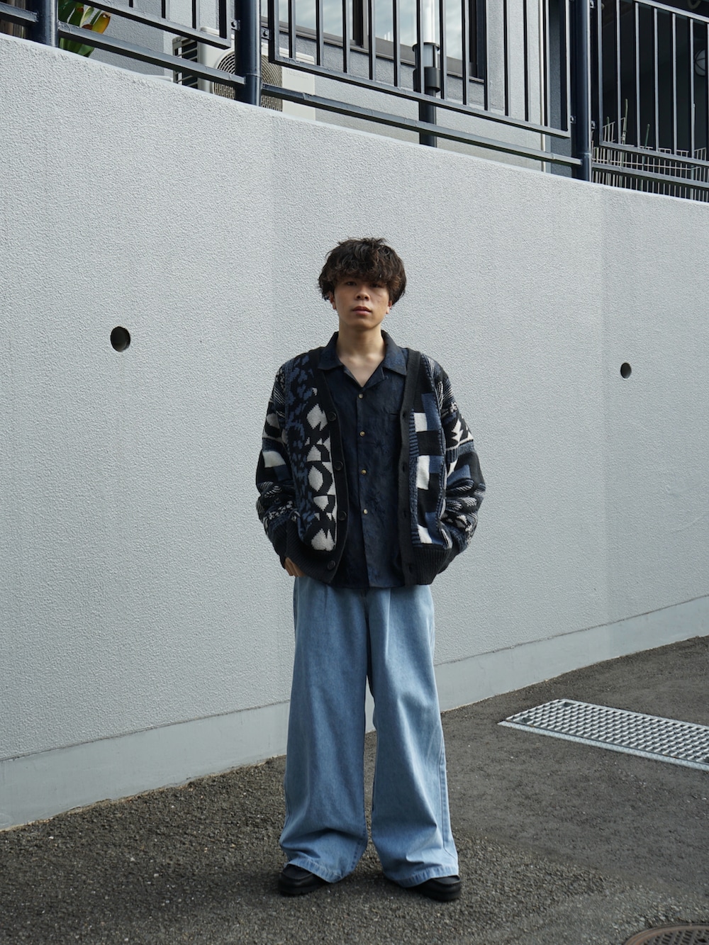 ブルー系のカーディガン/ボレロ、ブルー系のスラックス、ブラック系のブーツを着用したメンズの秋コーディネートの3枚目の写真