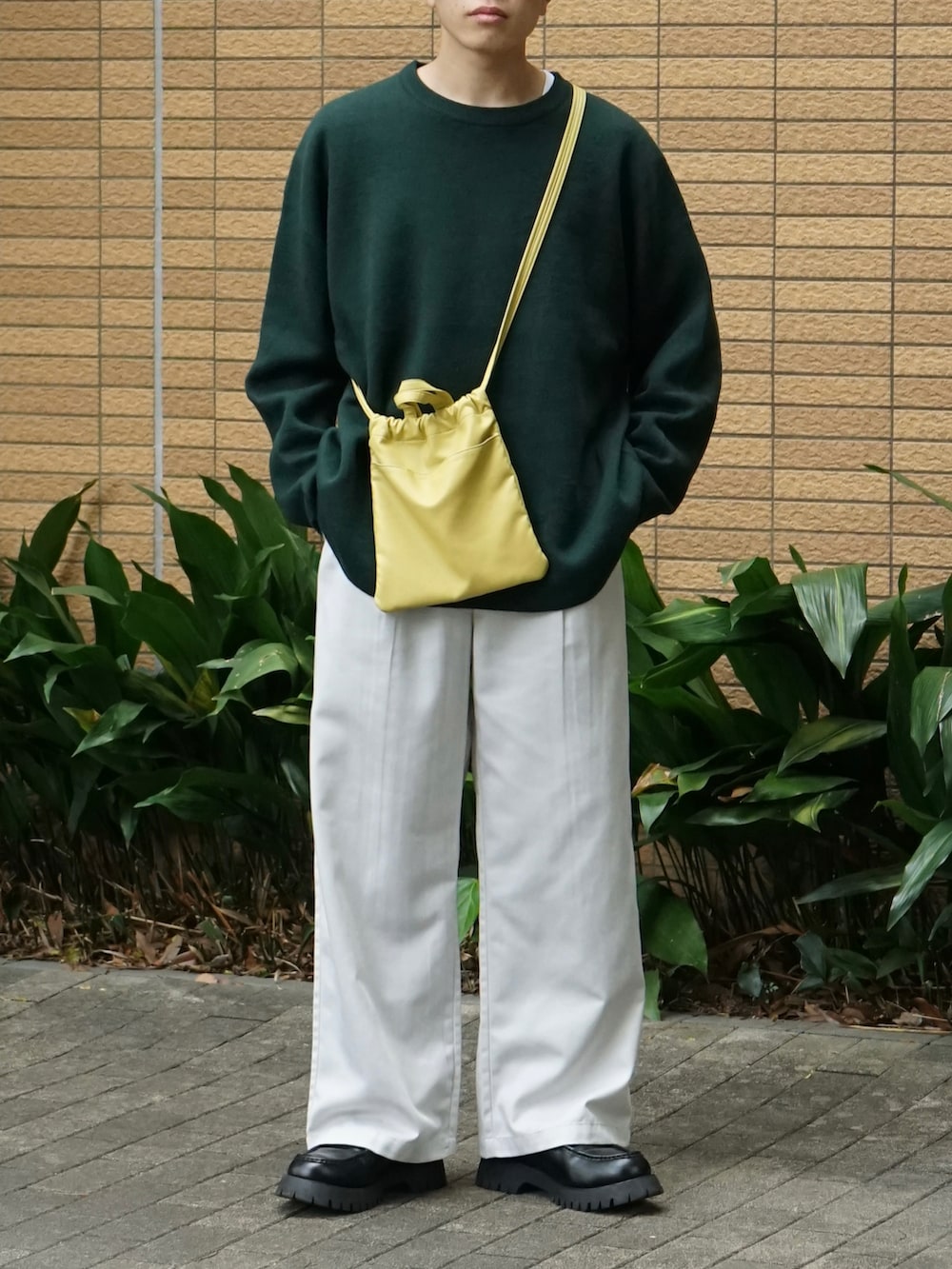グリーン系のニット/セーター、ホワイト系のチノパンツ、イエロー系のショルダーバッグを着用したメンズの秋コーディネートの5枚目の写真