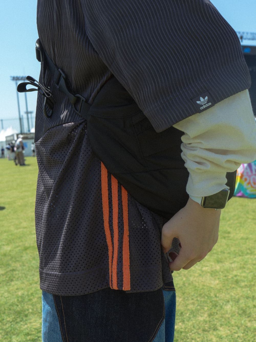 グレー系のトップス、ブラック系のショルダーバッグ、ブルー系のデニムパンツを着用したメンズの春コーディネートの4枚目の写真