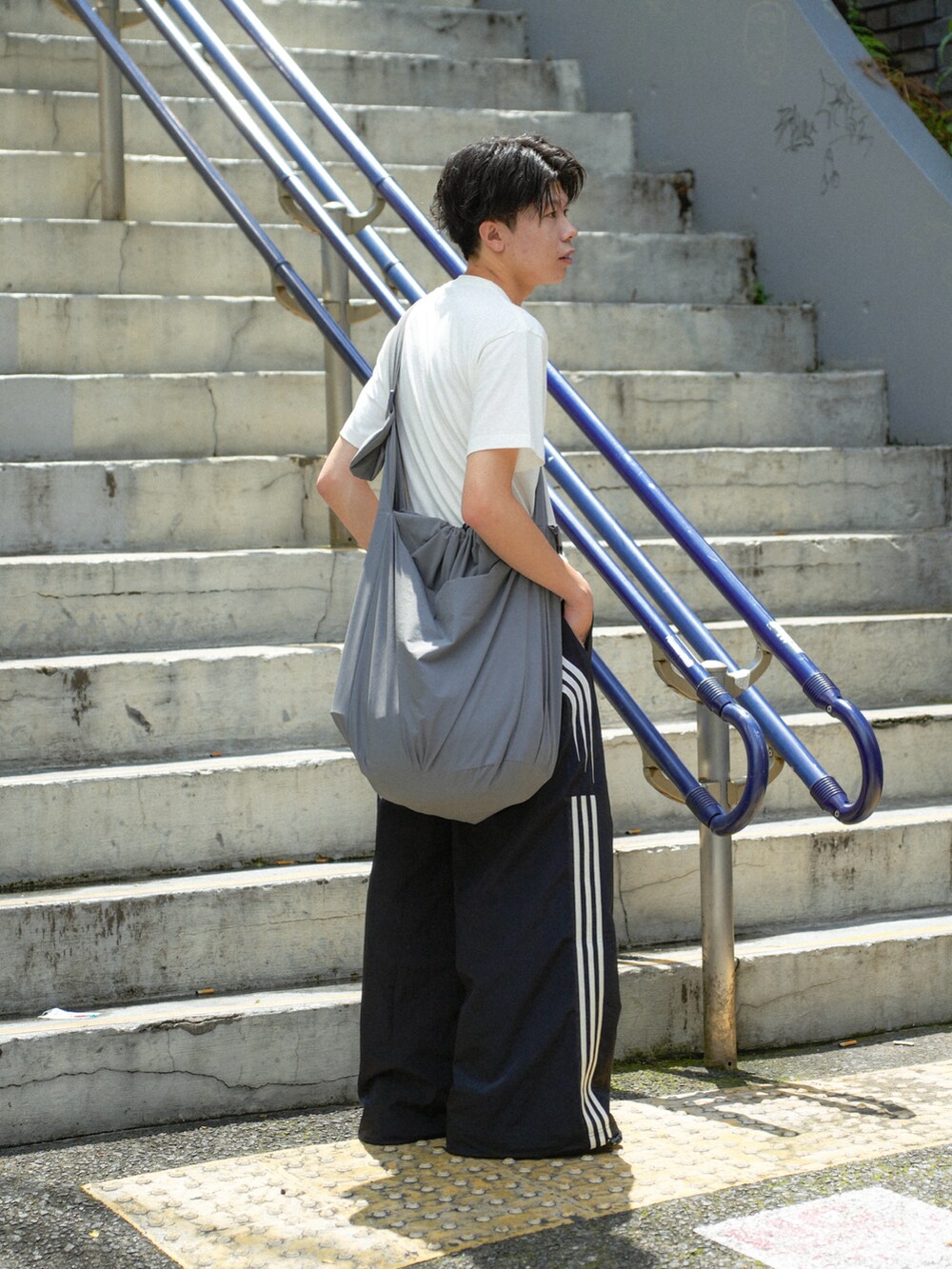 ホワイト系のTシャツ/カットソー、ブラック系のスウェットパンツ、グレー系のショルダーバッグを着用したメンズの夏コーディネートの3枚目の写真