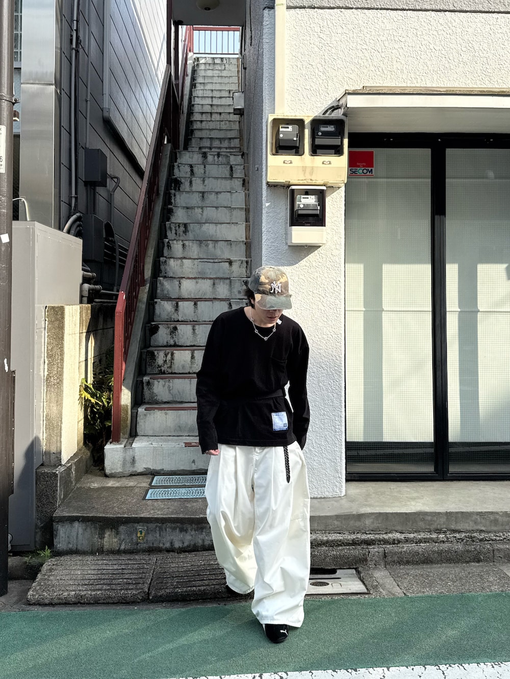 ブラック系のTシャツ/カットソー、ホワイト系のその他パンツ、ブラック系のボディバッグ/ウエストポーチを着用したメンズの春コーディネートの3枚目の写真