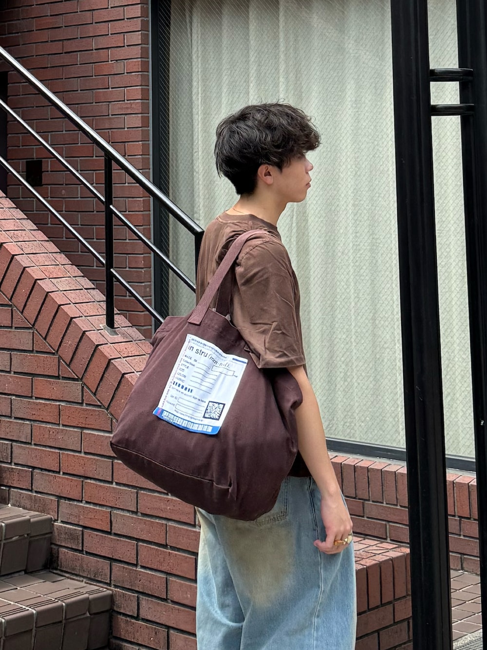 ブラウン系のTシャツ/カットソー、ブルー系のデニムパンツ、ブラウン系のトートバッグを着用したメンズの夏コーディネートの3枚目の写真