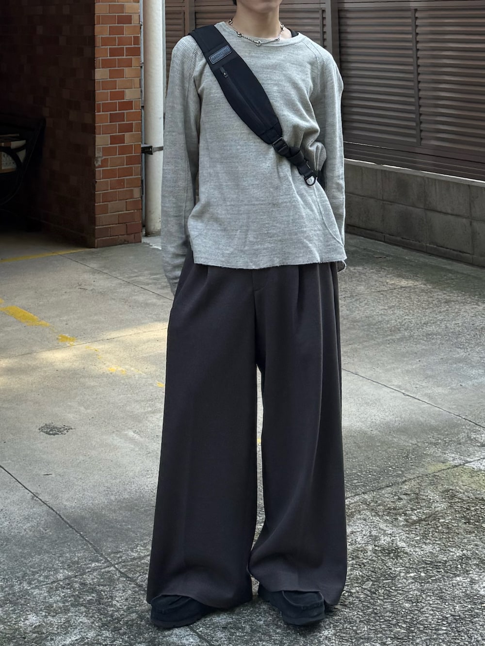 グレー系のTシャツ/カットソー、ブラウン系のスラックス、ブラック系のモカシン/デッキシューズを着用したメンズの秋コーディネートの4枚目の写真